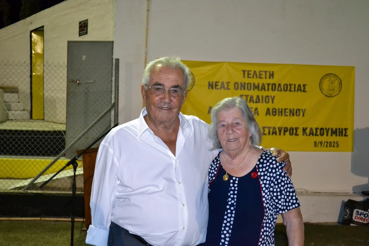 Two guests standing together beside the stadium during an evening ceremony